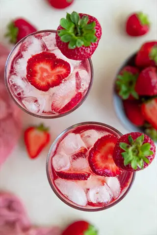 hydration with fresh strawberries: overhead view of iced drinks with strawberry slices and whole berry garnishes, surrounded by fresh strawberries
