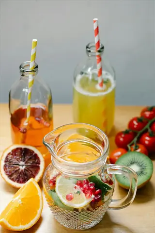 infused water pitcher with citrus fruits and berries, surrounded by fresh produce and bottled drinks - a hydration ritual