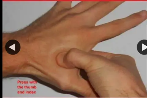instructional image showing fingertip pressure points: one hand presses palm of another using thumb and index finger, with red text 'press with the thumb and index'