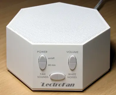 lectrofan white noise machine with control buttons for power, volume, fan sounds, and white noise settings on a wooden surface