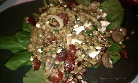 lentil salad with feta, red grapes, spinach, and sliced onions on dark plate (blog-style presentation)