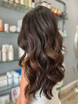 long wavy shiny healthy hair from back view in salon with hair care products on shelves