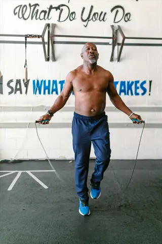 man performing jump rope cardio in a gym with motivational wall text