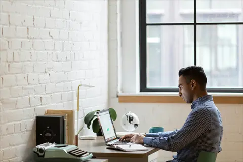 man working on laptop in modern office space - setting unshakeable boundaries for focused productivity