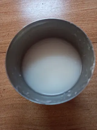 metal cup of traditional buttermilk on wooden table, creamy white fermented dairy drink