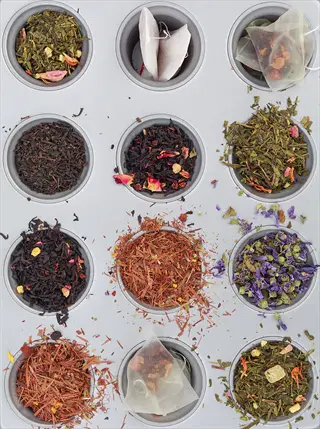 muffin tin displaying an herbal tea assortment with floral, green, and black tea blends in both loose leaf and tea bag forms