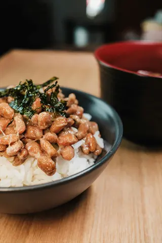 natto rice bowl with seaweed garnish and second bowl on wooden table