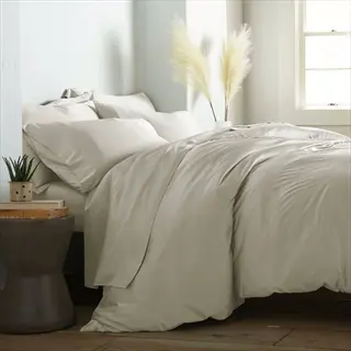 neatly made bed with light organic cotton bedding, pampas grass decor, and side table with books in a cozy bedroom - bedding comfort