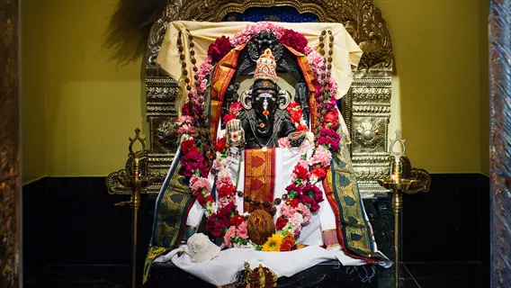 ornate ganesha idol adorned with flowers and fabrics in a temple shrine, representing a sacred space for mantra repetition focus during hindu worship