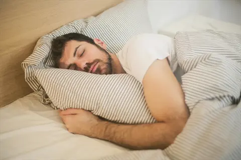 peaceful sleep person resting in bed with striped bedding, eyes closed in deep relaxation for sleep improvement