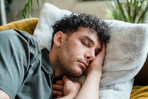 peaceful sleeping person resting on fluffy pillow in cozy indoor setting, demonstrating sleep quality improvement