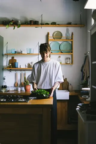 person cooking kitchen: man preparing fresh herbs in a sunny home kitchen, embodying learning new culinary skills