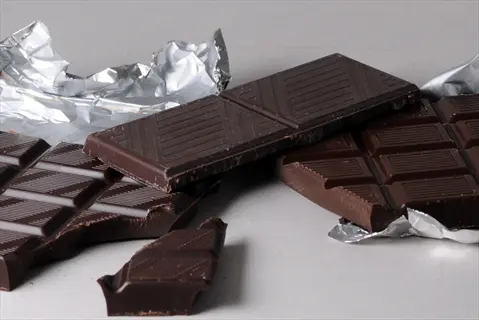 pieces of dark chocolate bars with foil wrappers, some partially unwrapped