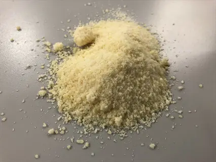 pile of nutritional yeast parmesan substitute on gray surface with scattered crumbs