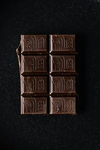 portioned dark chocolate bar divided into squares with embossed designs on dark background