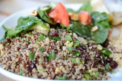 quinoa brown rice bowl with spinach salad, tomatoes, and cranberries - grain upgrades meal