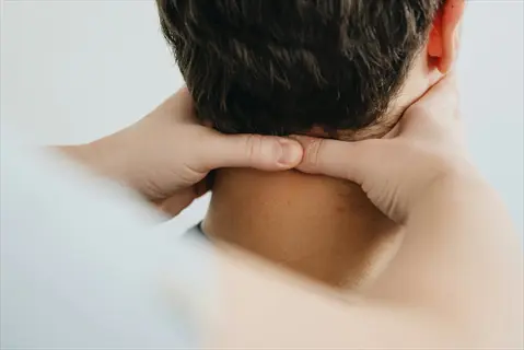 rear view of hands performing self neck massage in therapeutic setting