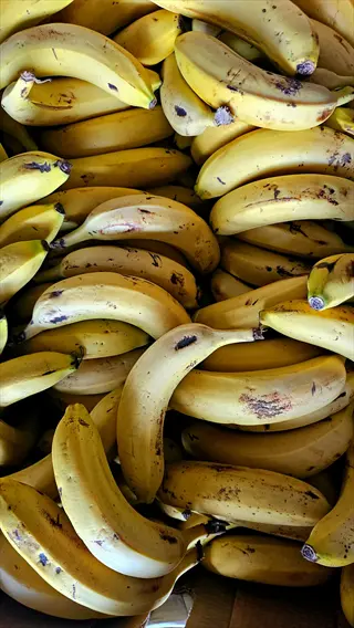 ripe bananas bunch: densely packed yellow bananas with brown spots filling entire frame, close-up overhead view