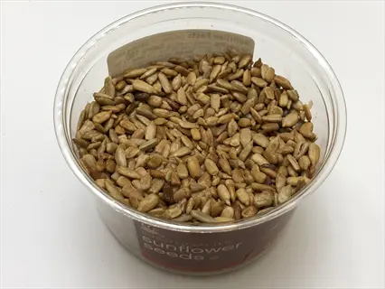 roasted sunflower seeds in clear plastic container with visible 'sunflower seeds' branding and nutrition facts label