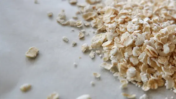 rolled oats (whole grains) scattered on parchment paper surface