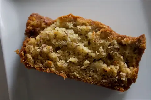 single slice of almond flour banana bread with moist texture and visible banana flecks on a white plate