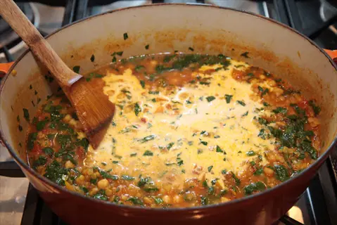 spinach lentils stew in a pot on the stove, stirred with wooden spoon - iron-rich meal