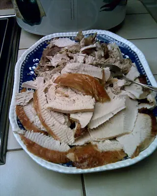 turkey slices plate with serving fork on kitchen countertop, slow cooker visible in background - tryptophan sources