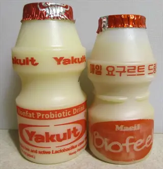 two bottles of yogurt probiotics, yakult and maeil biofeel, on a counter