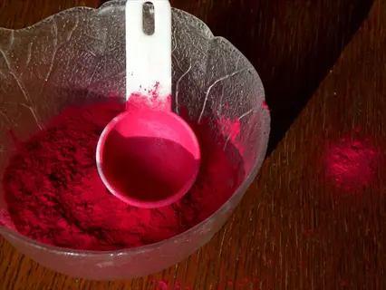 vibrant pink beetroot powder in glass bowl with measuring scoop on wooden surface, natural superfood supplement