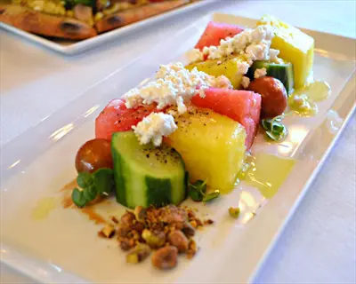 watermelon feta salad with cucumber, cherry tomatoes, pistachios, and herbs on a white plate