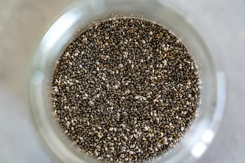 whole chia seeds in a glass jar showing dark and light seed varieties