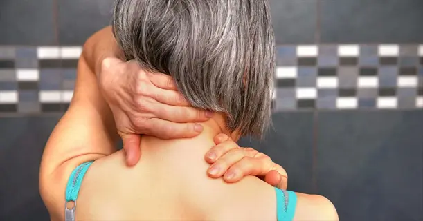 woman demonstrating self massage neck technique with hands on cervical and upper back muscles, showing home relief method for tension
