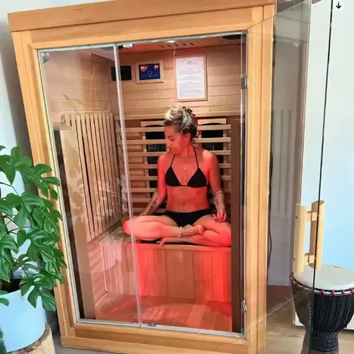 woman in black bikini meditating inside a modern infrared sauna for relaxation and health benefits