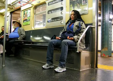 woman meditating on subway during commute (public transport meditation), seated in train car with destination signs and other passengers