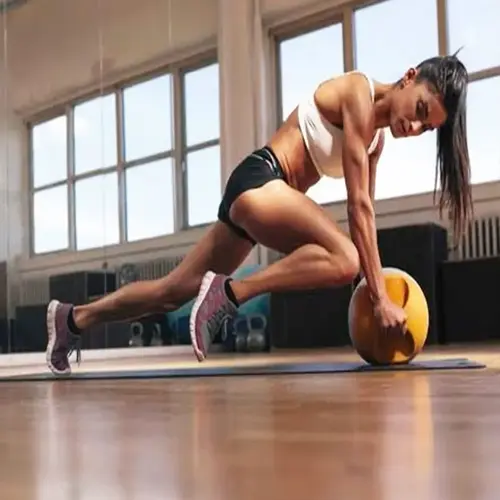 woman performing high-intensity interval training with medicine ball in modern gym