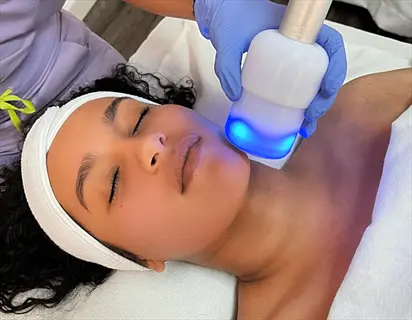 woman receiving ice pack neck cold therapy with blue light device during spa treatment, therapist's gloved hands visible