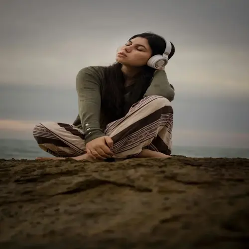 woman relaxing with headphones on a beach rock, embracing nature