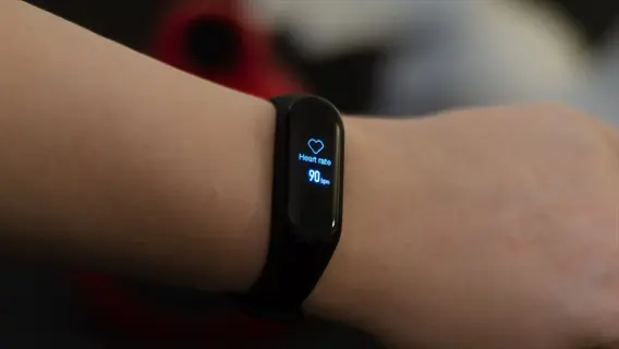 wrist wearing a heart rate monitor fitness tracker displaying 90 bpm measurement on its digital screen